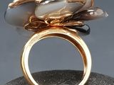 gold plated ring with black and white stones on top of a rock