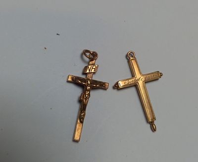 deux croix en or, chacune ornée d'une croix, posées sur une table