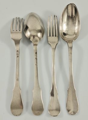quatre cuillères en argent et une fourchette sont alignées sur une surface blanche