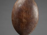 a wooden sculpture of a pear on a black stand