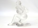 a white statue of a woman sitting on a skateboard