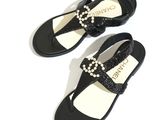 black and white sandals with pearls on them on a white surface