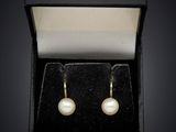 a pair of pearl earrings in a black box