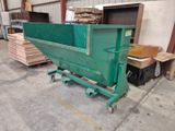 a green dumpster sitting on a dolly in a warehouse