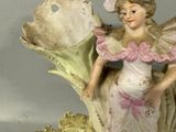a figurine of a little girl sitting on a leaf