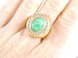an image of a woman ' s hand holding a ring with a green stone on it