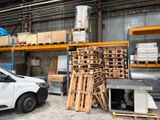 une camionnette blanche garée dans un entrepôt, à côté de palettes de bois