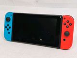 a red and blue nintendo switch lite sitting on a white surface