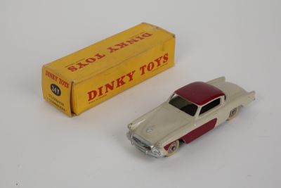 une petite voiture « Dinky Toy » avec sa boîte posée à côté sur une surface blanche