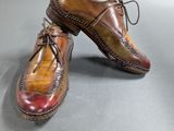 two pairs of brown and red shoes sitting on top of a gray surface