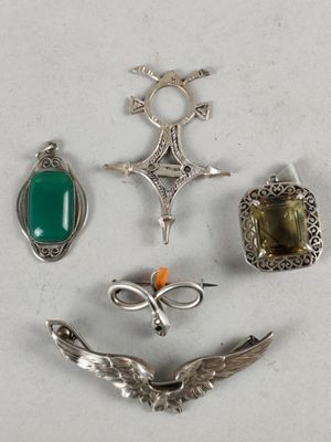 several silver and green jewelry items are arranged on a white surface
