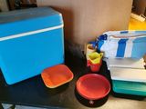 une table sur laquelle sont posés une glacière, des assiettes et des tasses