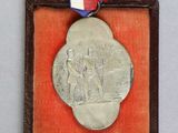 une vieille médaille en argent dans un écrin en velours rouge, entourée d'un ruban