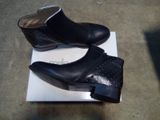 pair of black leather ankle boots sitting on top of a white box