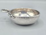 a small silver bowl with a handle on a table