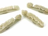 four pieces of carved jade hair clips on a white surface