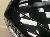 a black car parked in a parking lot with a sticker on the hood