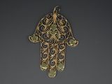 a close up of a gold hametle with green stones on it