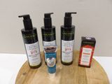 three bottles of olive oil and two packages of soap on a wooden tray