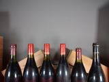 six bottles of red wine sit in a wooden box on a table