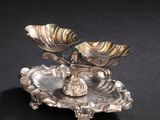 une assiette en argent ornée d'une fleur sur un fond noir