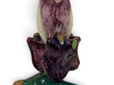a figurine of a purple flower on a green leaf