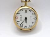 une montre de poche en or avec un cadran blanc sur une surface blanche