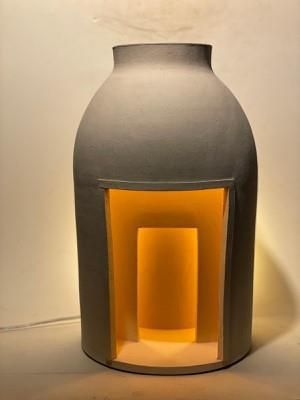 un grand vase gris dans lequel brille une lumière jaune