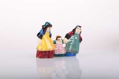 three figurines of people sitting on a white surface