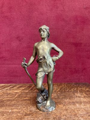 bronze figurine of a boy holding a stick and a dog