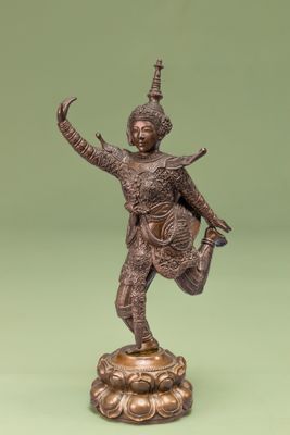statue en bronze représentant une femme en train de danser sur un socle, sur fond vert