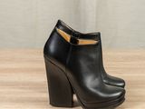 a pair of black leather ankle boots sitting on top of a wooden table