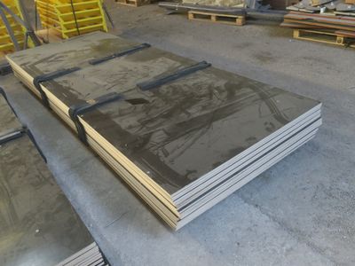 plusieurs piles de tôles d'acier empilées les unes sur les autres dans un entrepôt