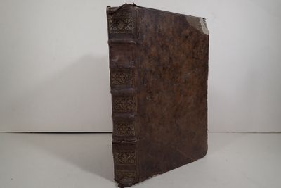 un vieux livre posé sur une table à côté d'un mur blanc