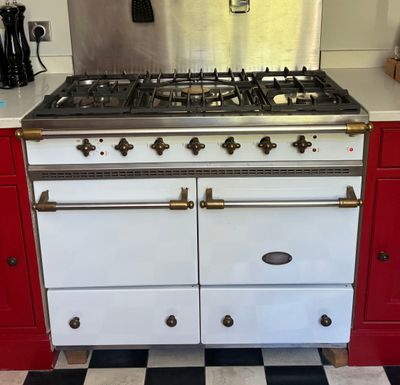 une cuisinière blanche et rouge dans une cuisine au sol en damier noir et blanc