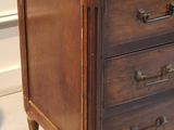 a small wooden chest of drawers on display in a room