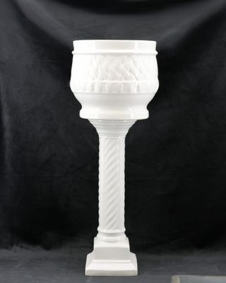 une image représentant un verre blanc posé sur un socle, sur fond noir