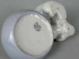 porcelain figurine of two elephants holding a bowl on a gray surface