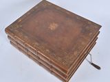 an old leather bound book sitting on top of a white surface