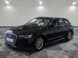 L'Audi break noire est garée dans une grande pièce au sol carrelé en damier.