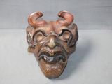 a ceramic mask with horns on it on a table
