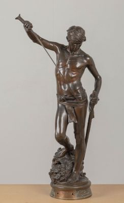 bronze statue of a man holding a sword on a wooden table