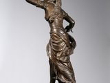a bronze statue of a woman holding a bird on top of a rock