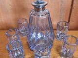 une carafe en verre et des verres à shot posés sur une table