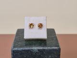 a pair of gold stud earrings sitting on top of a marble block