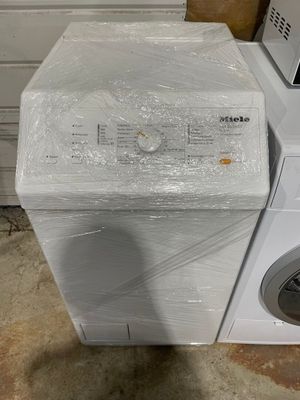 une machine à laver blanche posée à côté d'une pile de cartons