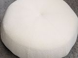 a white round pillow sitting on the floor next to a cup of coffee