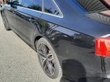 the rear end of a black car parked in front of a building