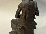 statue of a man sitting on a stool with his back to the camera