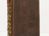 an old book with a brown cover sitting on top of a white table